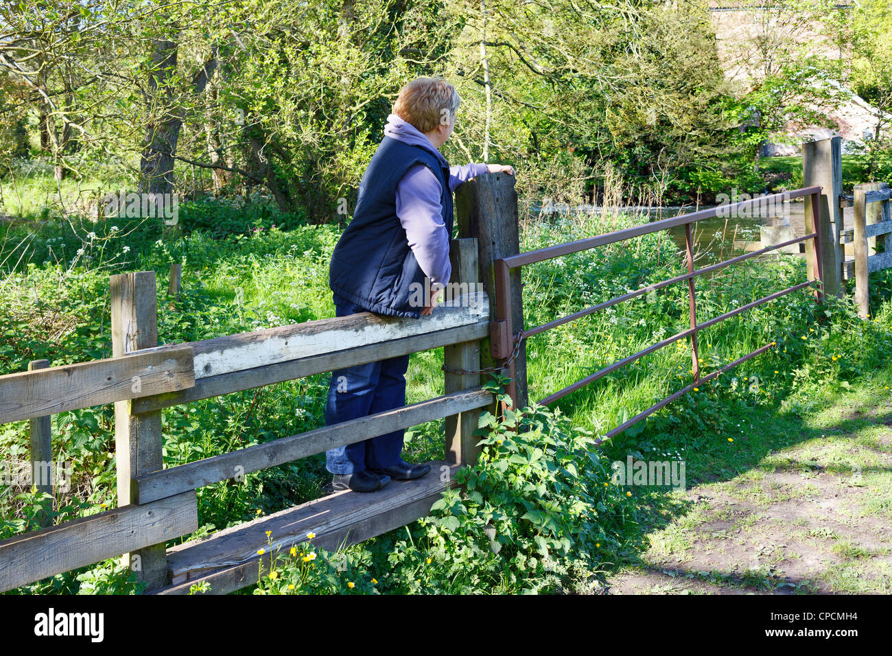 Una donna che si arrampica sul montante verticale sulla strada alzaia lungo il lato del "fiume Bure' di Norfolk, Regno Unito Foto Stock