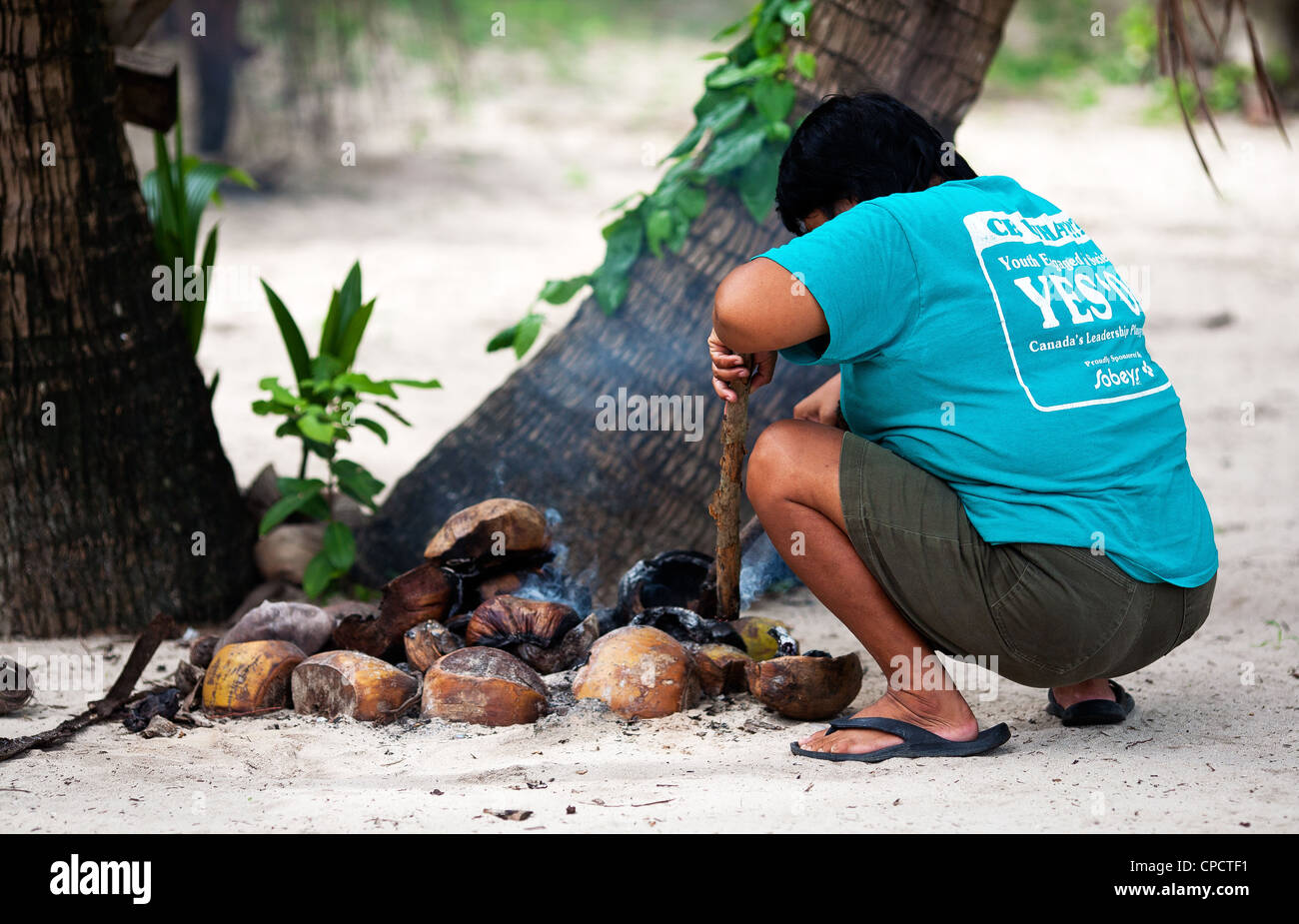 Una donna filippina stokes un incendio di gusci di noce di cocco per mantenere le zanzare presso la baia di El Nido, PALAWAN FILIPPINE. Foto Stock