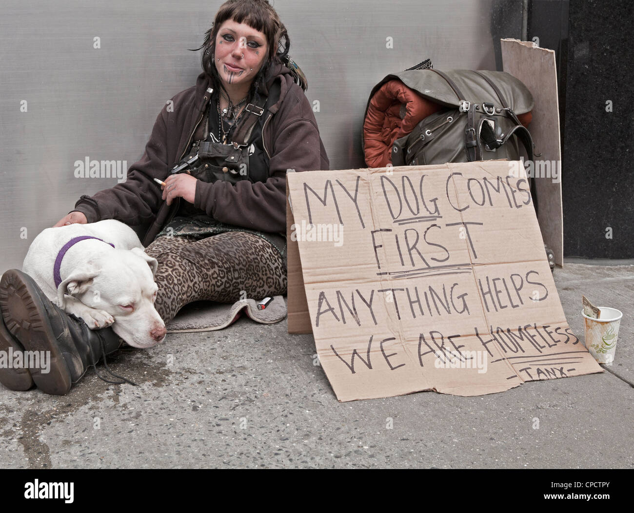 Una donna senza casa si siede con il suo cane su un marciapiede a Manhattan a New York City. Foto Stock