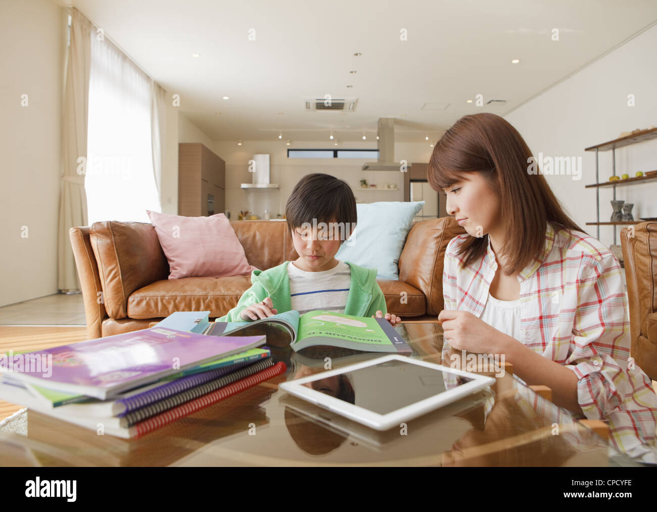 La madre e il figlio a studiare in una stanza vivente Foto Stock