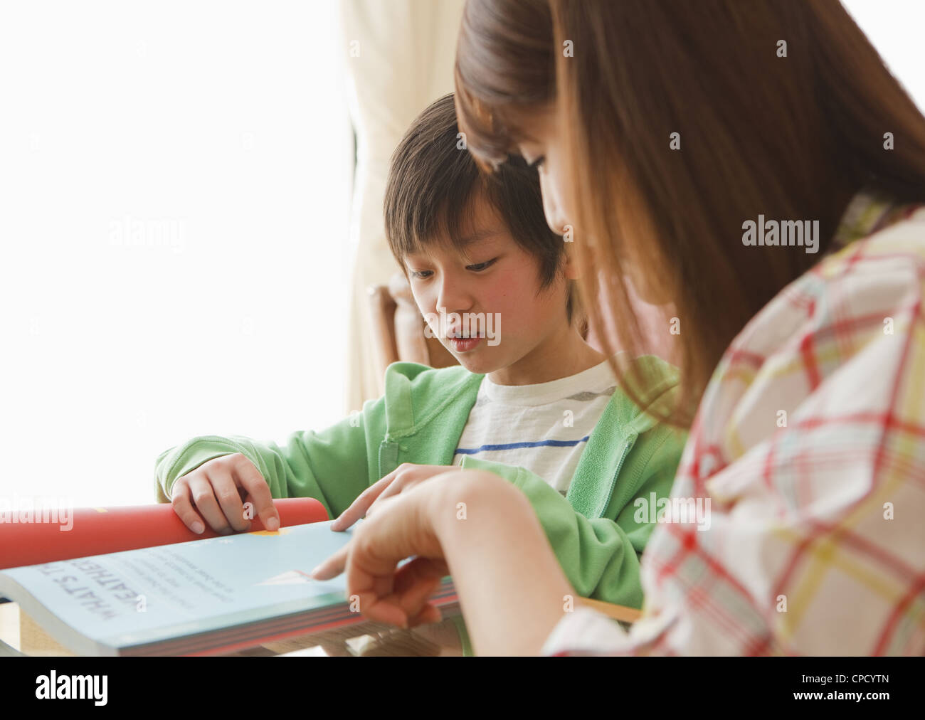 La madre e il figlio a studiare in una stanza vivente Foto Stock