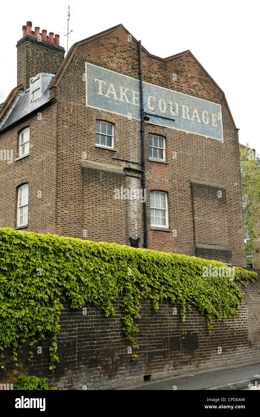 Dipinto 'prendere coraggio' birra pubblicità sul lato dell'edificio, London, Regno Unito Foto Stock