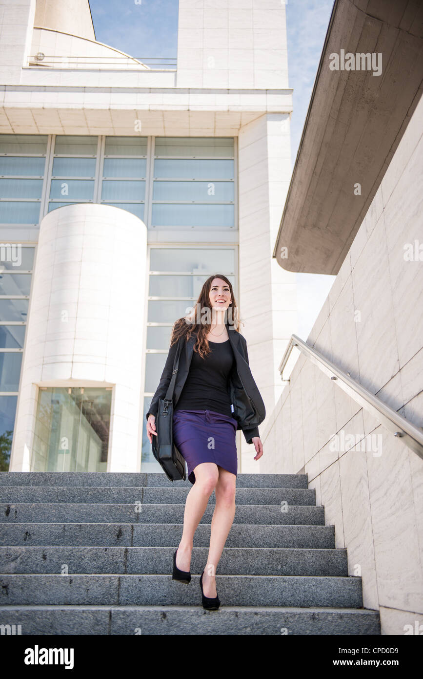 Young business woman in fretta - camminare sulle scale con la borsa per notebook Foto Stock