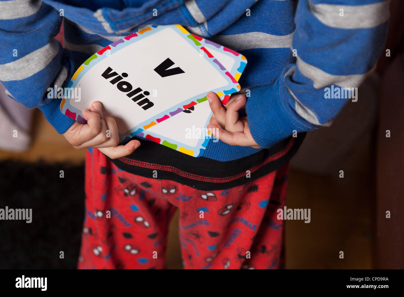 Bambino nasconde alfabeto carta dietro il suo dorso Foto Stock