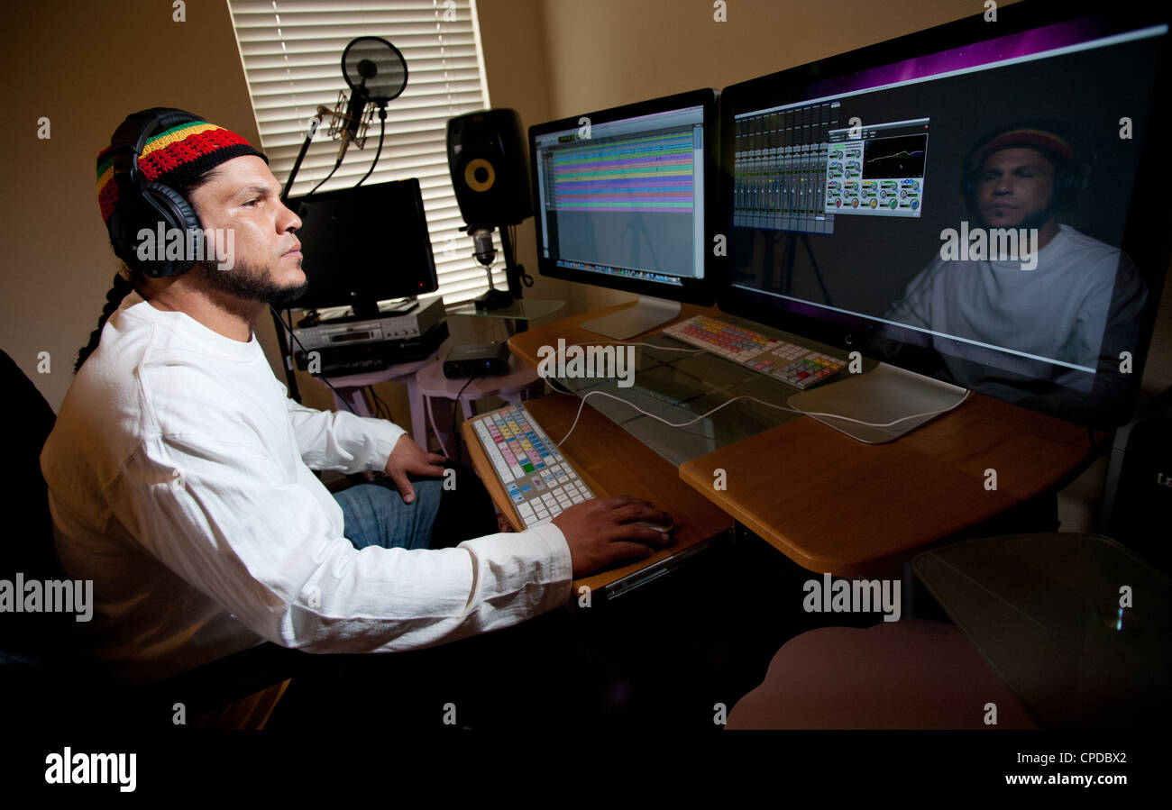 Un giovane multi-etnico uomo si siede in un suono booth lavora al computer. Foto Stock