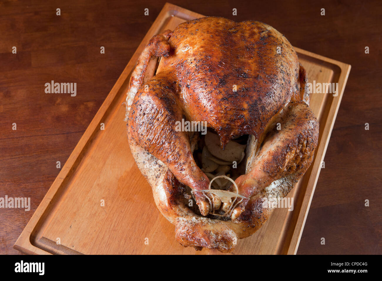 Vista frontale di arrosto di tacchino intero sul tagliere di legno con cipolla all'interno. Foto Stock