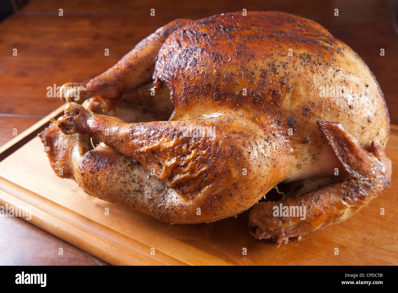 Arrosto di tacchino intero riposo dopo la cottura sul tagliere di legno. Foto Stock