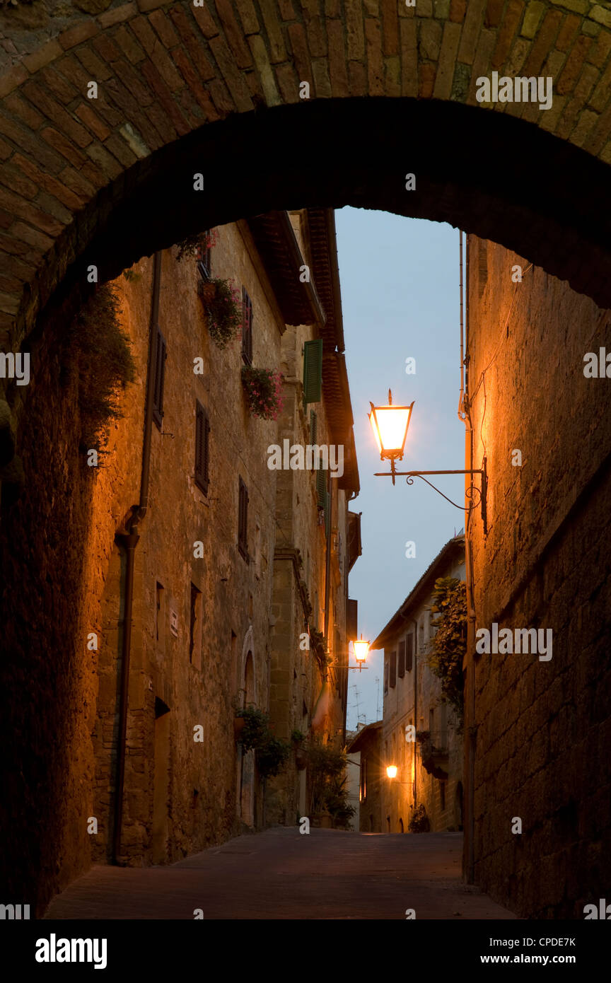 Un inizio di mattina vista attraverso un arco in pietra nella cittadina collinare di Pienza, Val d'Orcia, Toscana, Italia, Europa Foto Stock