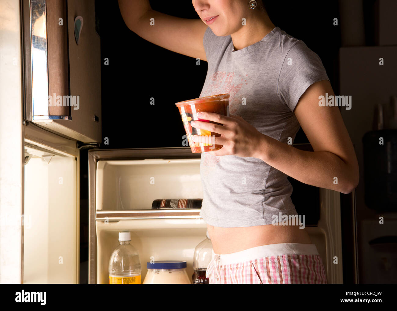 Una donna prowls frigorifero a tarda notte Foto Stock