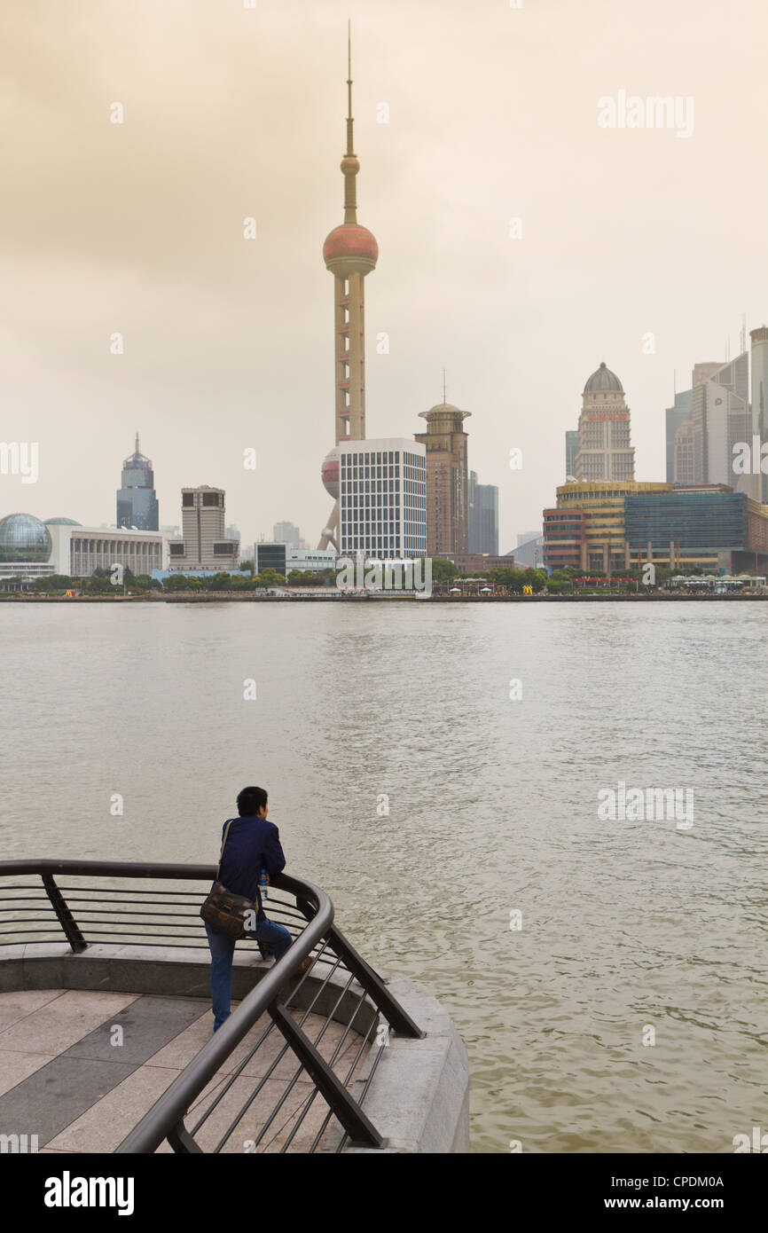 Un uomo che guarda la Oriental Pearl Tower e lo skyline di Pudong attraverso il fiume Huangpu dal Bund, Shanghai, Cina e Asia Foto Stock