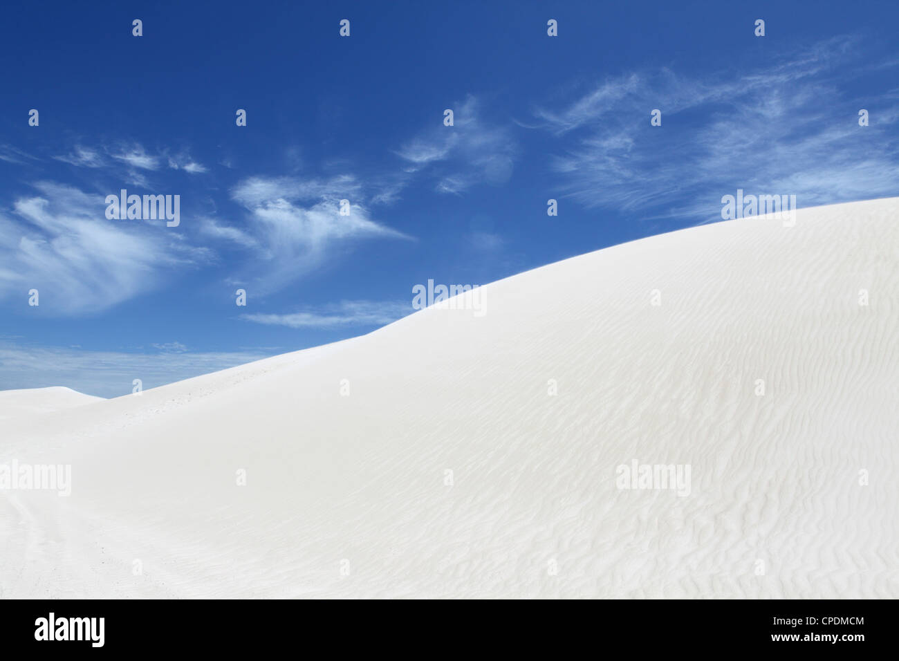 Il vento soffia sabbia bianca lungo la parte superiore sulla duna, sotto un cielo blu, a Lancelin, Australia occidentale, Australia Pacific Foto Stock