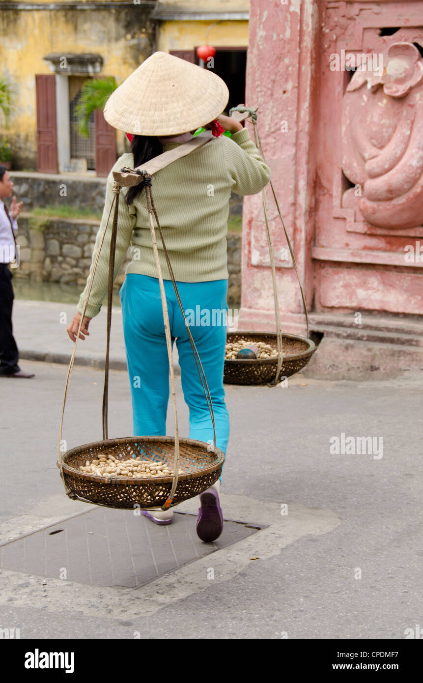 Il Vietnam, da nang, villaggio di Hoi An. abitante di un villaggio tipico portando cesti di arachidi. Foto Stock