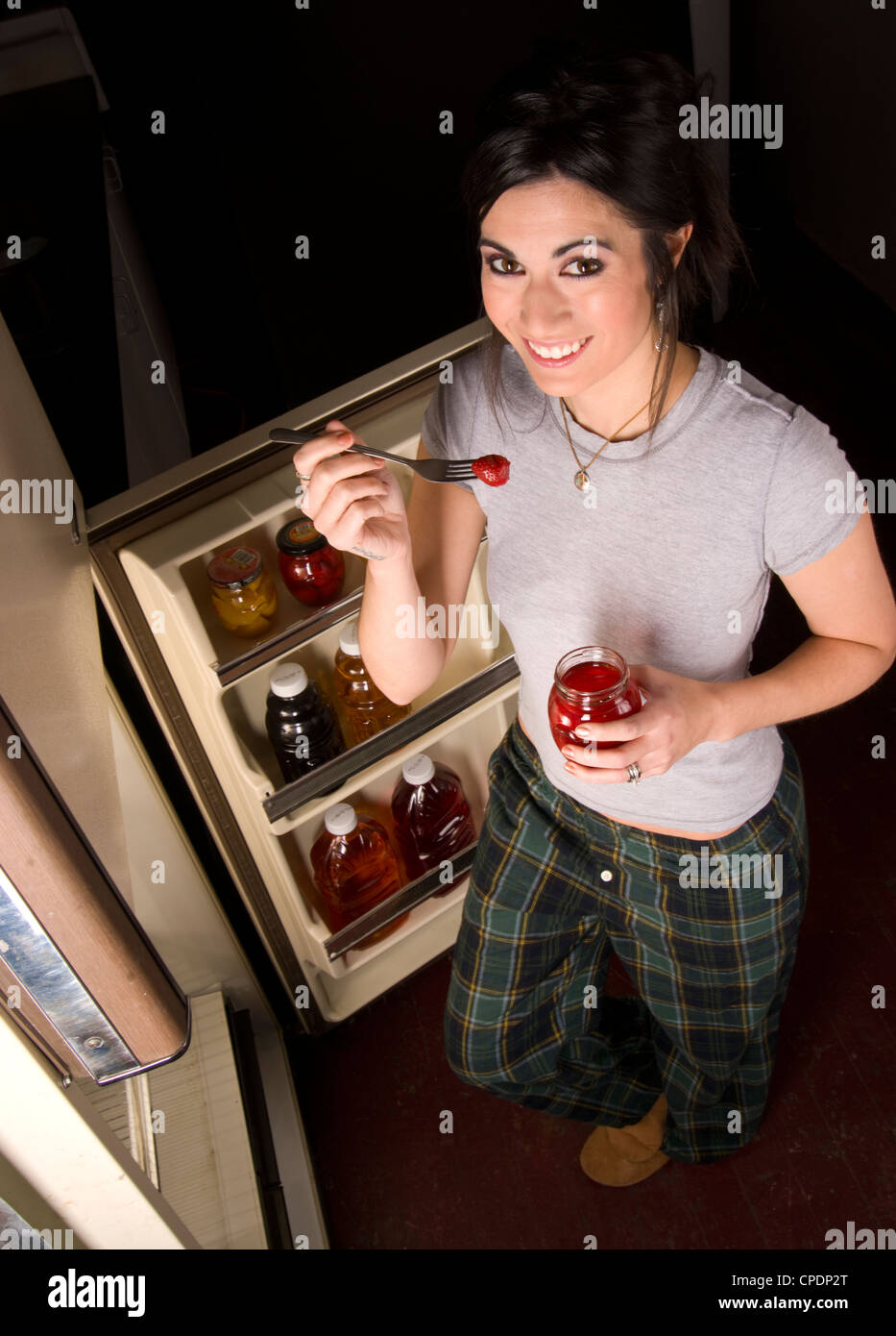 Una donna raids il frigorifero a tarda notte Foto Stock