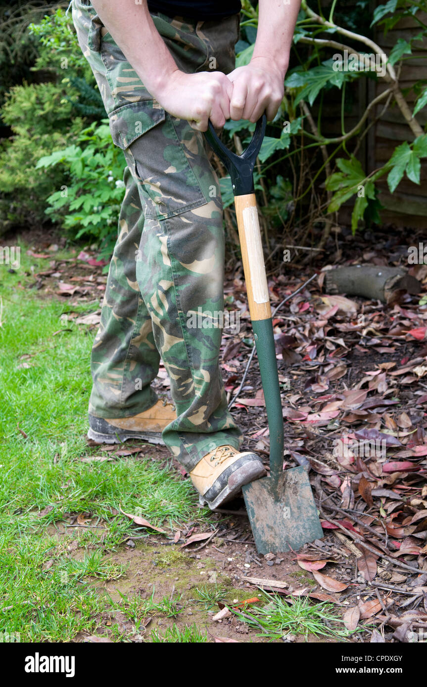 Uomo caucasico scavando fuori confine con giardino vanga nel giardino in Bristol, Regno Unito Foto Stock