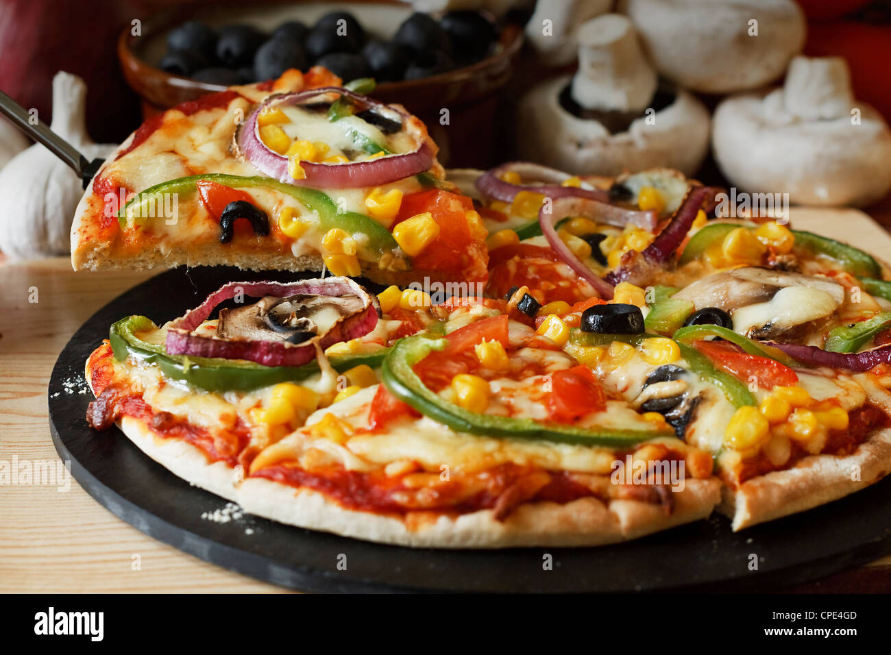 Pizza vegetariana fetta con un condimento di funghi, pomodori, peperoni, cipolle, granturco dolce e olive Foto Stock