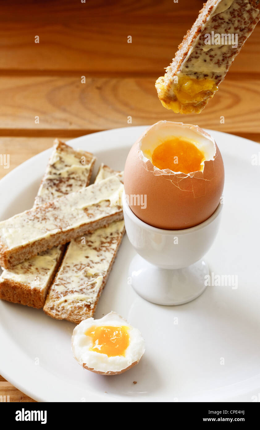 Un toast imburrato soldati essendo immersi in un uova sode in un uovo cup Foto Stock