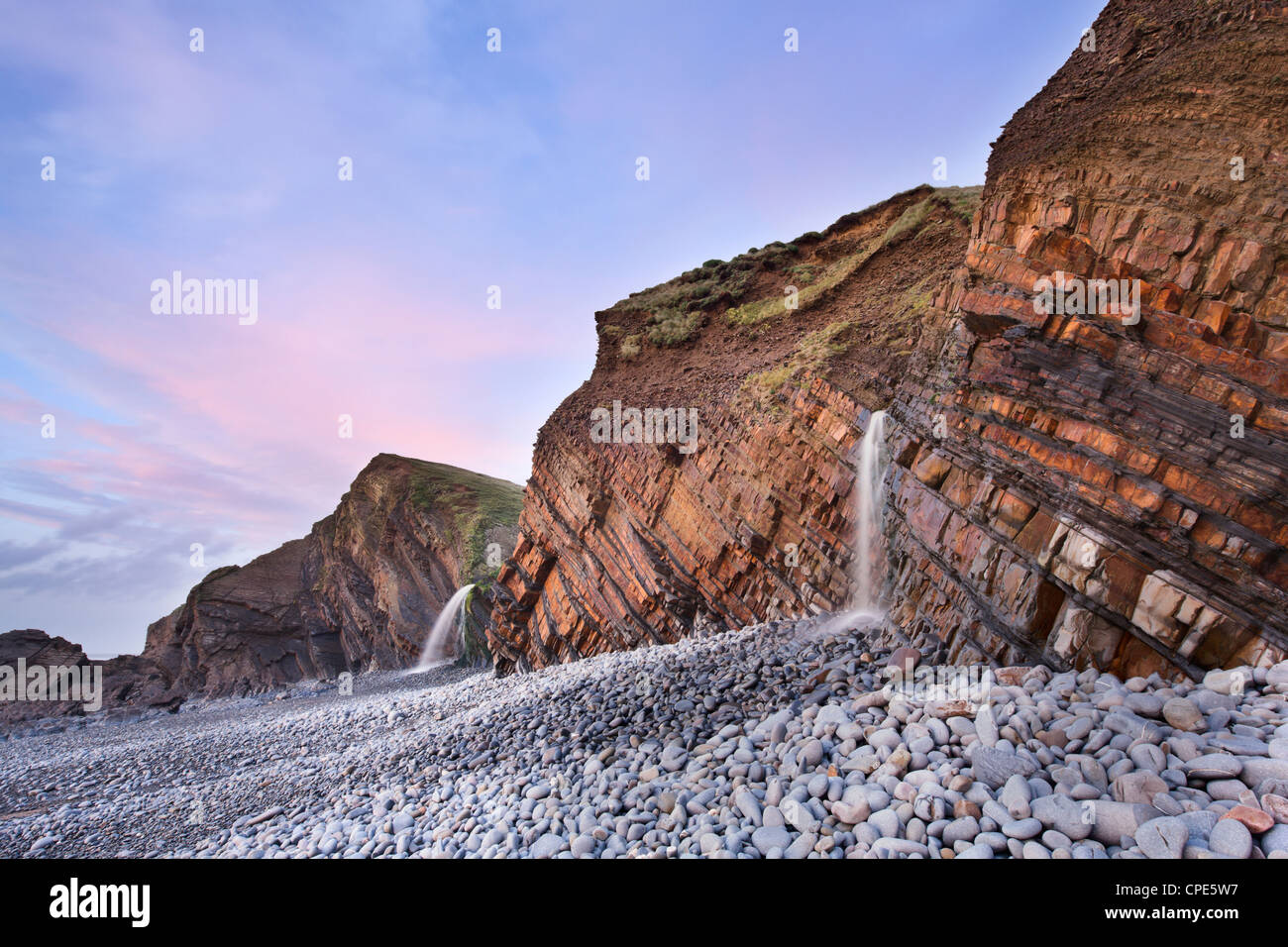 Arenaria di strati di roccia e cascate a Sandymouth spiaggia al tramonto, vicino a Bude, Cornwall, England, Regno Unito, Europa Foto Stock
