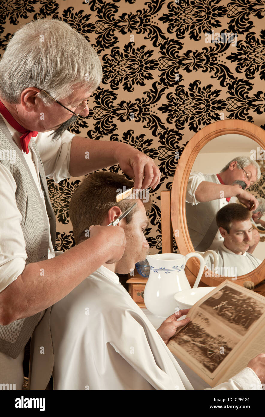 Barbiere il taglio dei capelli di un cliente in un antico barbiere  vittoriano (l'antica rivista è dal 1910 Foto stock - Alamy