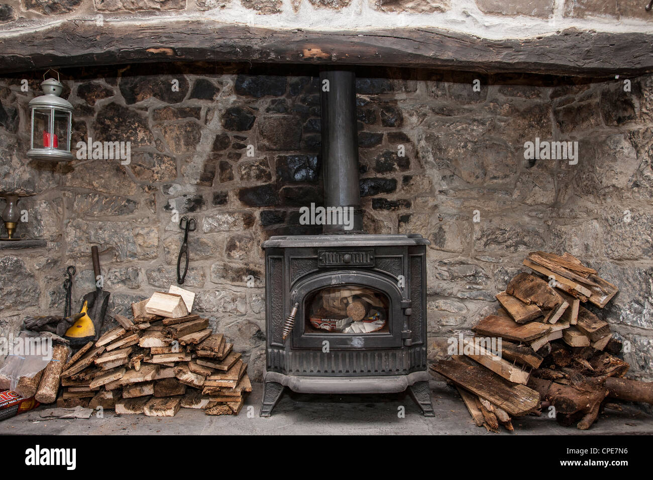 Legna da ardere accanto a una stufa a legna, interno Cottage irlandese Foto Stock