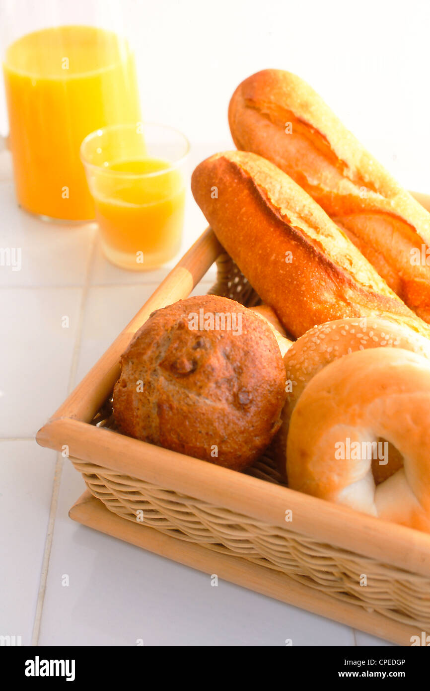 Un assortimento di pane in vassoio di legno e succo di arancia Foto Stock