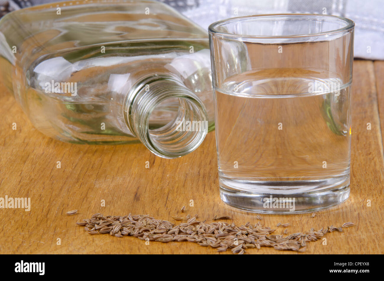 Il cumino schnapps in un bicchiere e seme su una tavola di legno Foto Stock