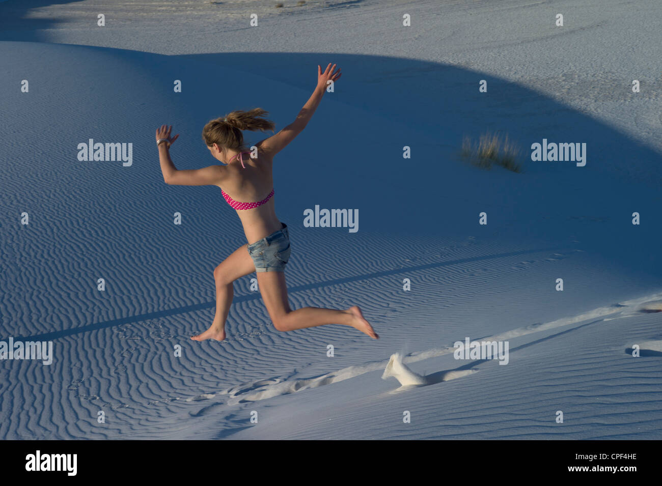 Giovane donna salta giù per una duna di sabbia a White Sands National Monument, Nuovo Messico, STATI UNITI D'AMERICA Foto Stock