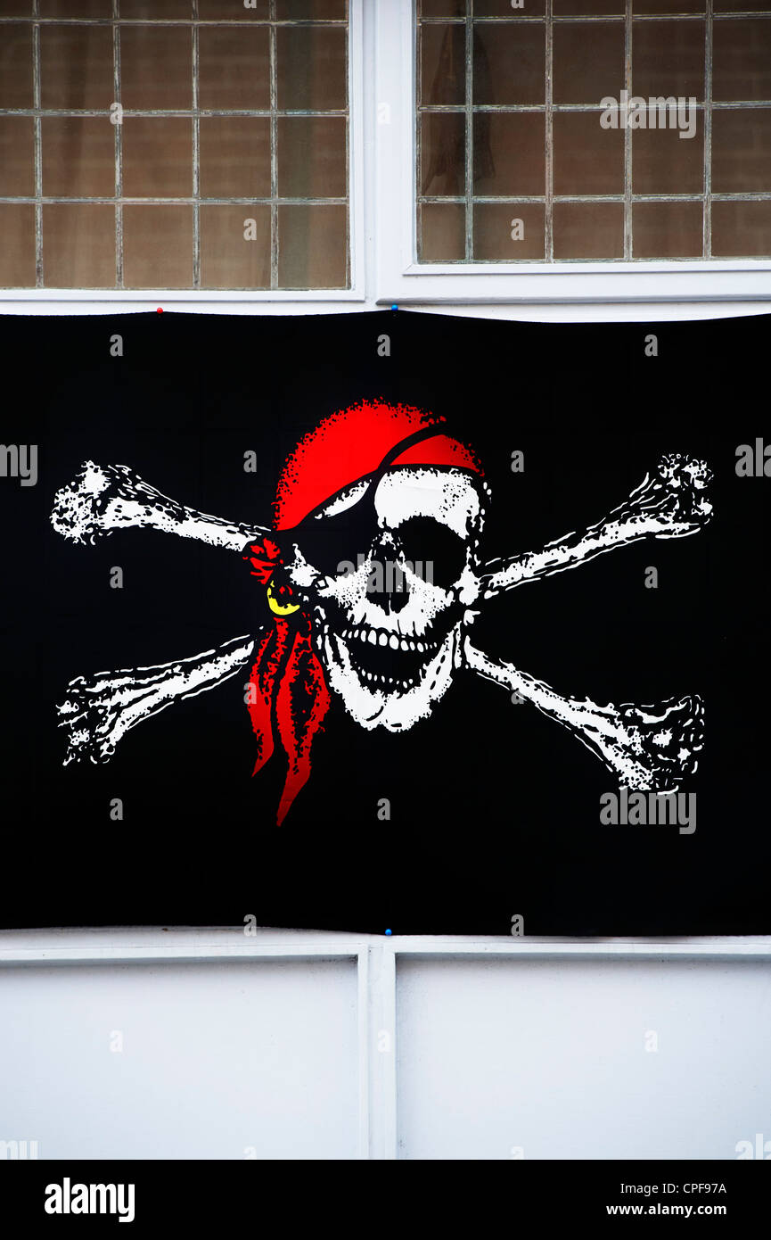 Jolly Roger pirate flag nella finestra della barra, Brixham, Devon, Inghilterra Foto Stock