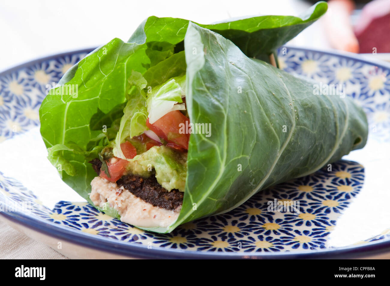 Dado condita focaccia, guacamole, lattuga romana, salsa e dado di mandorle formaggio avvolto in una foglia di Collard. Foto Stock