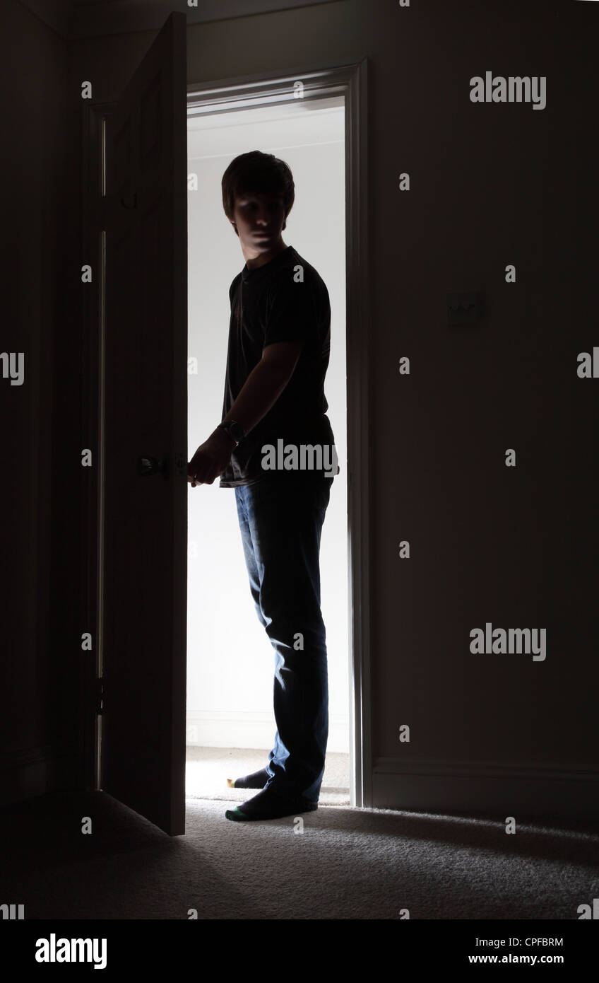 Silhouette di un giovane maschio di apertura di una porta. Foto Stock