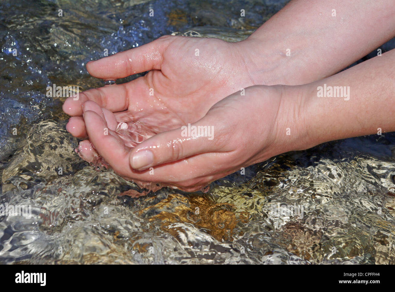 Mani di una giovane donna rinfrescante nella fresca e acqua pura di un ruscello di montagna Foto Stock