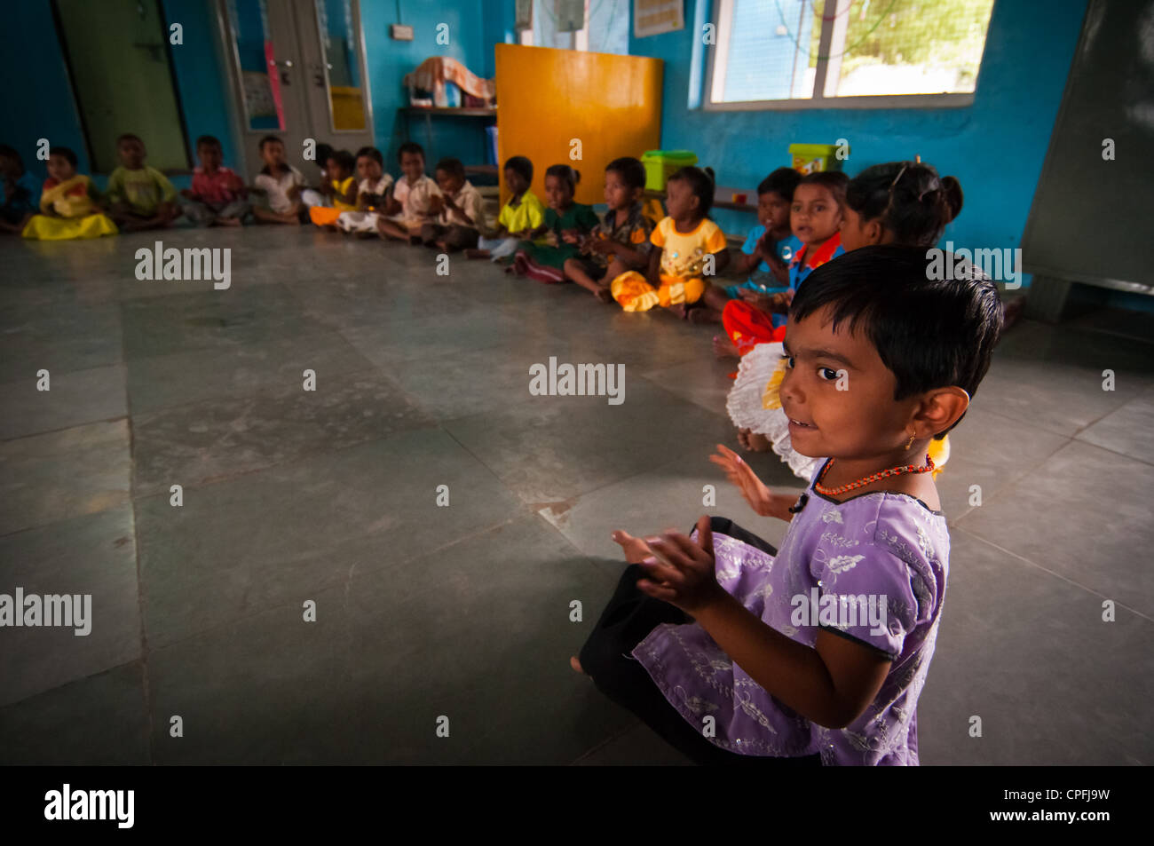 Un cerchio di bambini Indiani seduto sul pavimento in classe a cantare. Foto Stock