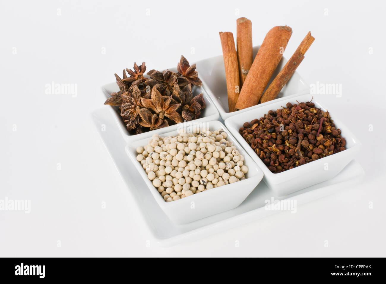 Anice stellato, cannella, pepe bianco e Coriandolo seme nel vaso in ceramica su sfondo bianco Foto Stock