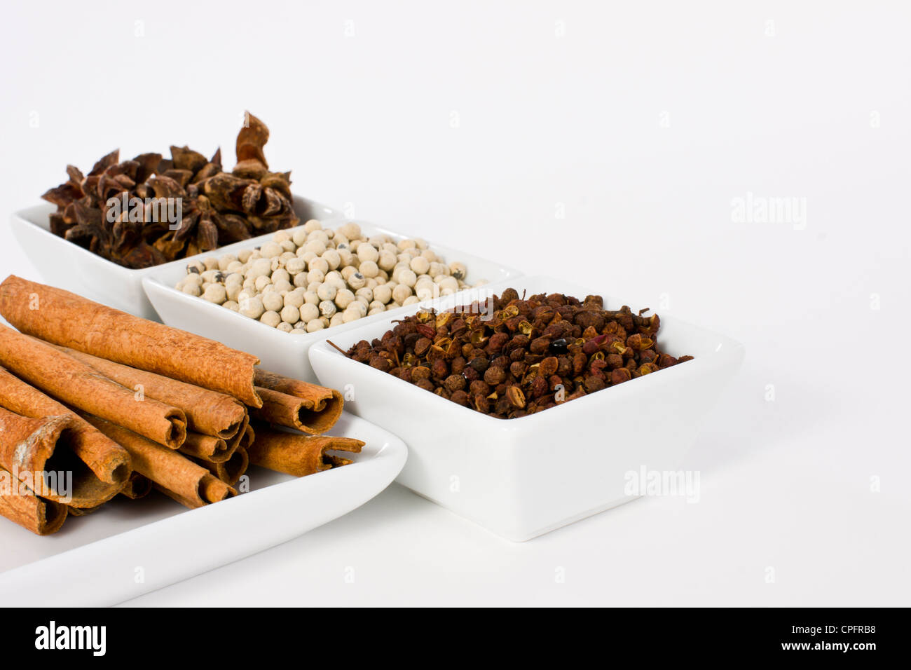 Anice stellato, cannella, pepe bianco e Coriandolo seme nel vaso in ceramica su sfondo bianco Foto Stock