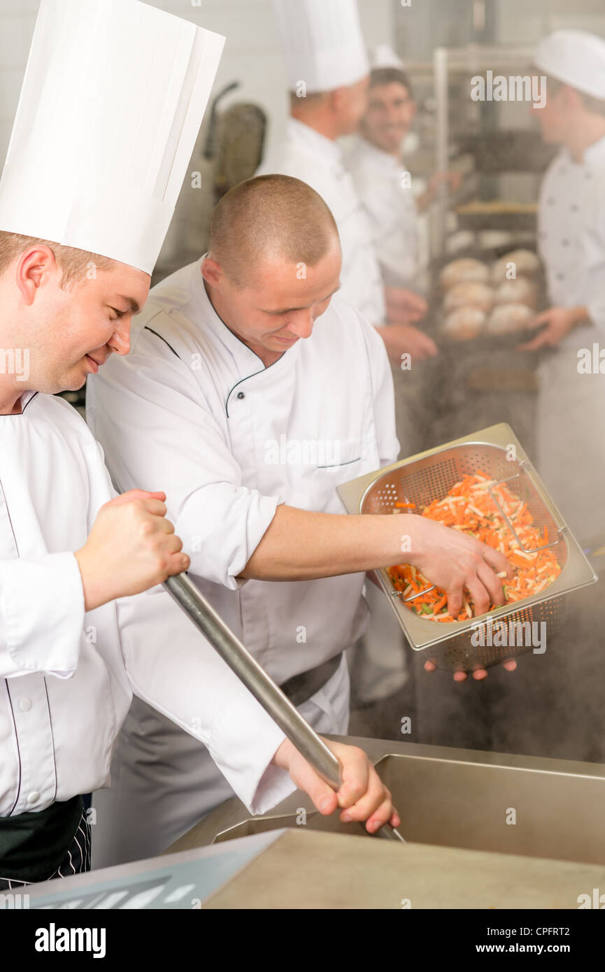 Professionale chef cucinare con il team di preparare il cibo in cucina industriale Foto Stock