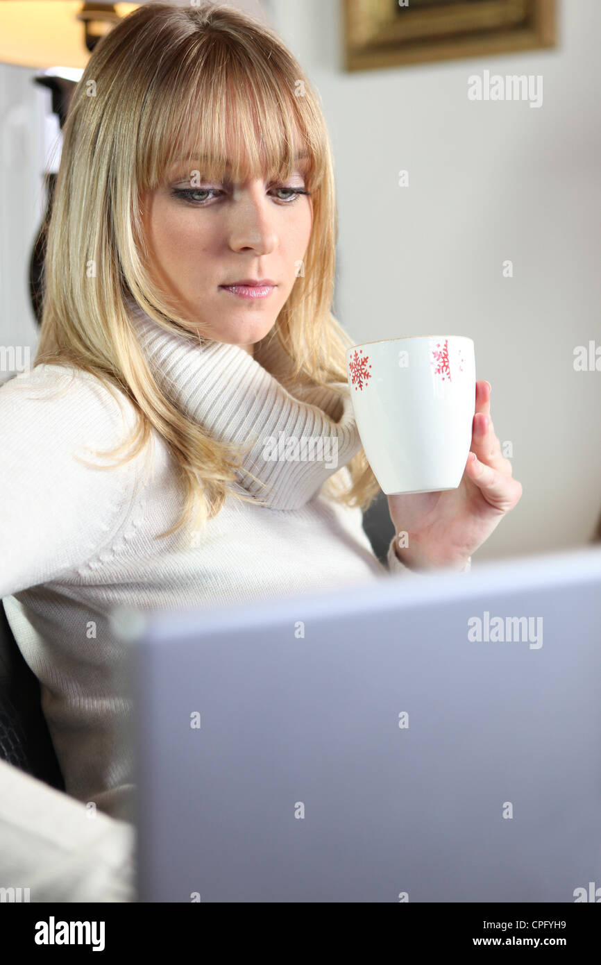 Carino giovane biondo un caffè mentre si lavora sul computer portatile Foto Stock