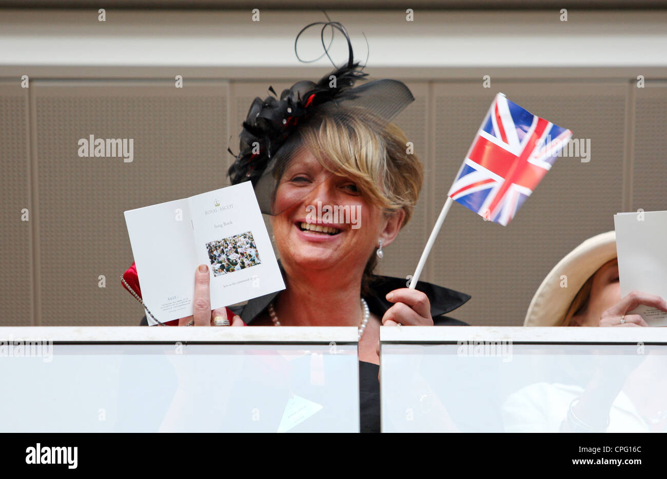 Donna con una piccola bandiera del Regno Unito e una Royal Ascot song book a corse di cavalli, Ascot, Regno Unito Foto Stock