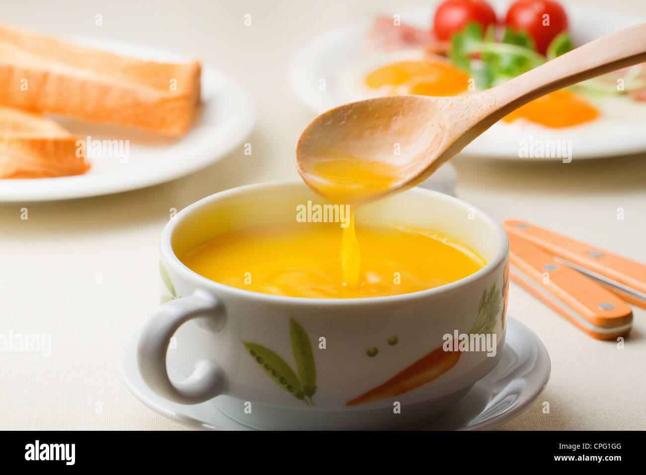 Tazza di zuppa di giallo misto da cucchiaio di legno Foto Stock