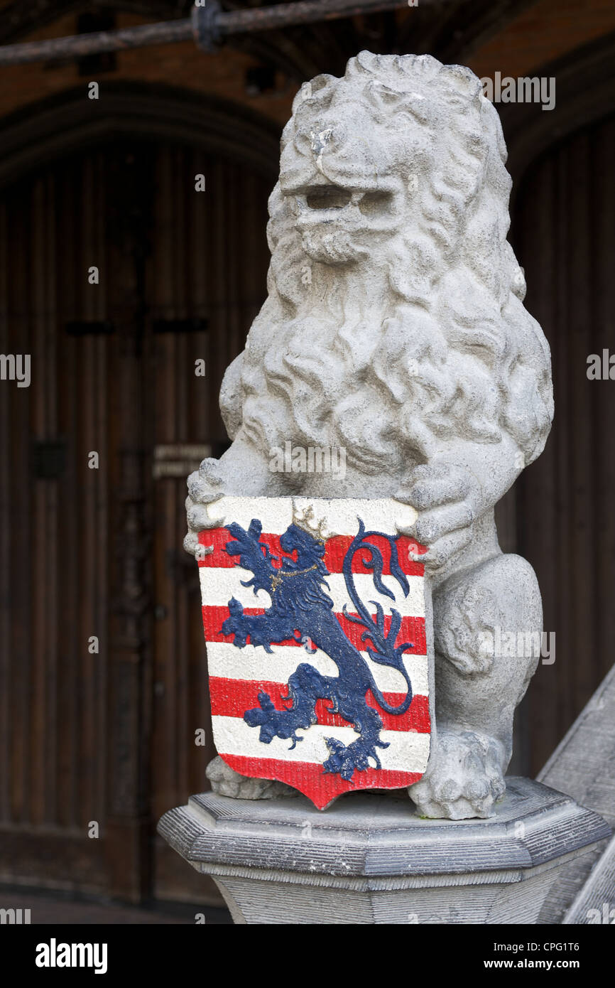 Pietra scolpita la statua di un leone azienda uno scudo con lo stemma del Fiandre - strisce rosse e bianche con un blue lion. Foto Stock