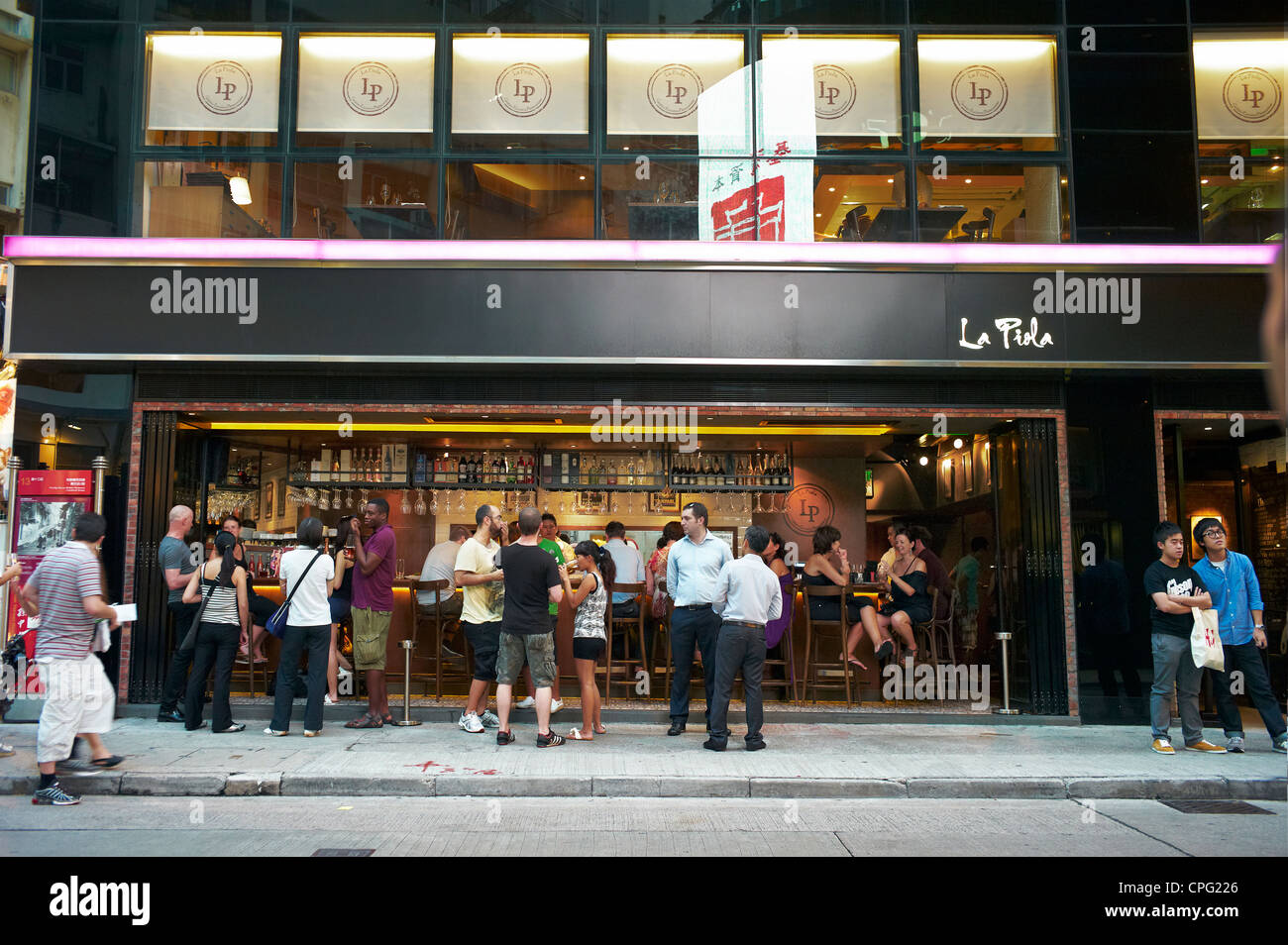 Gli espatriati, turisti, stranieri e gente del posto al di fuori di un affollato ristorante e bar di Soho, Hong Kong, Cina. Foto Stock