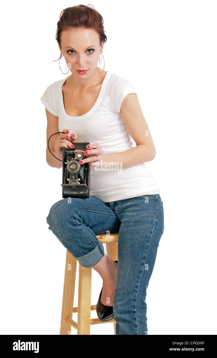 Attraente giovane donna con una piegatura vintage fotocamera e a distanza per l'otturatore. Foto Stock