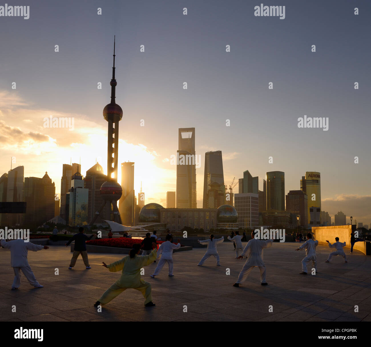 Tai chi esercizio di gruppo rivolto verso il sorgere del sole e il Pudong alte torri dal Bund Shanghai in Cina Foto Stock