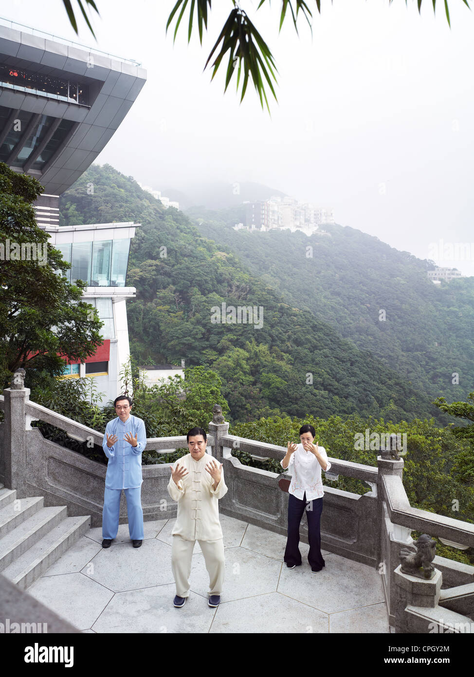 Un Tai Chi Il Maestro e il suo allievo pratica le arti marziali al picco con la torre di picco in background. Foto Stock