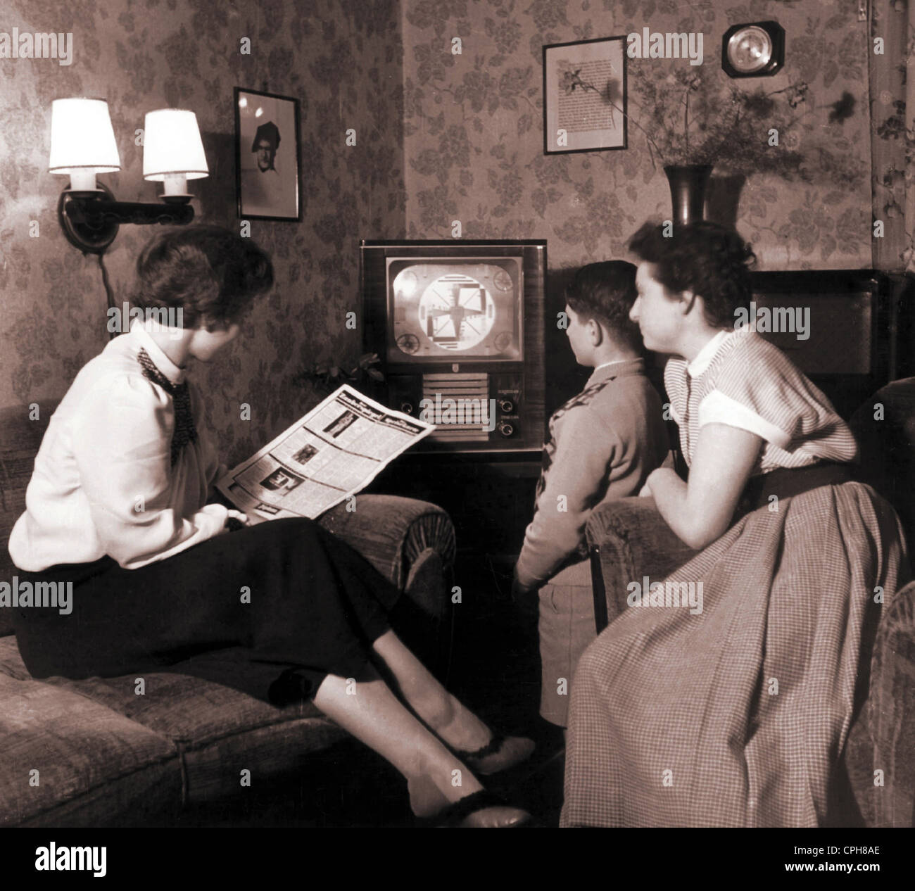 Trasmissione, televisione, famiglia durante l'inizializzazione della televisione tedesca, in attesa di programma, donna sta cercando nella guida TV 'Hoerzu', prima sera del programma, stazione di trasmissione NWDR, televisore Philips 'starling Nesting box', Hannover, Germania, 25.12.1952, Additional-Rights-Clearences-non disponibile Foto Stock