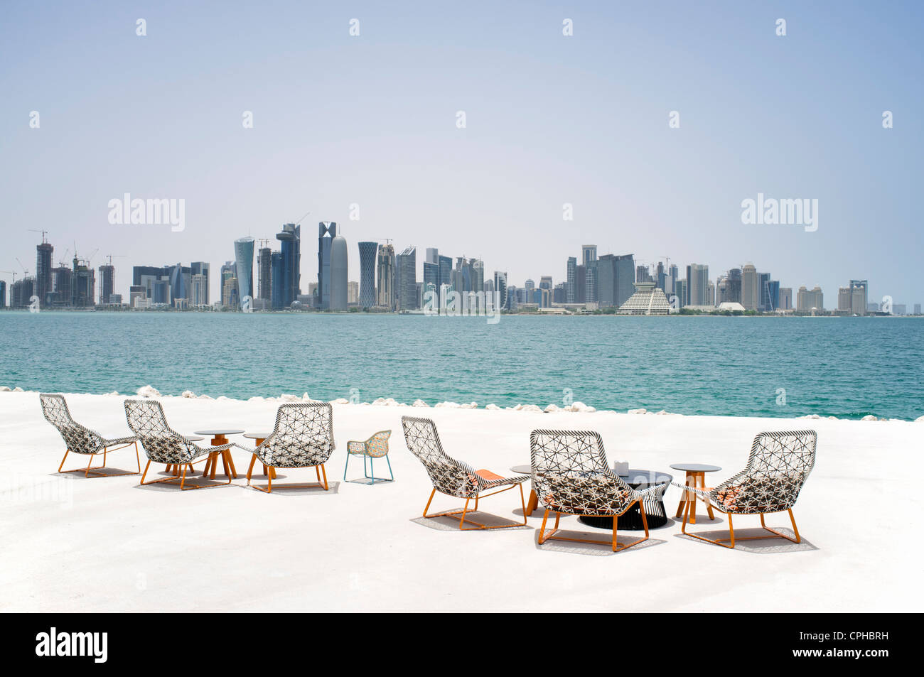 Moderni posti a sedere esterni a waterfront cafe con vista sullo skyline di Doha in Qatar Foto Stock