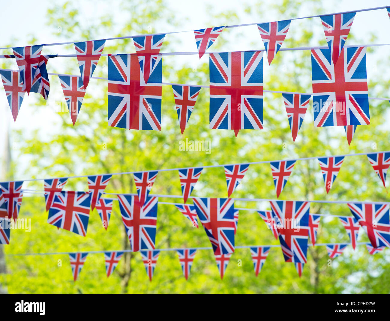 Union Jack flag bunting di fronte alberi soleggiato Foto Stock