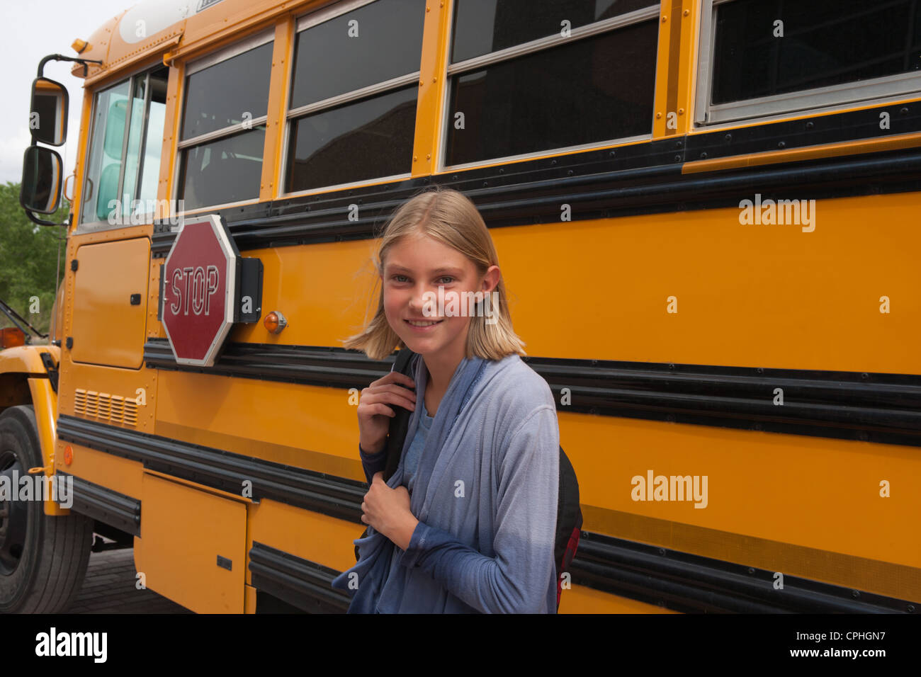 La scuola media di studente a sorridere di fronte alla sua scuola bus. Foto Stock