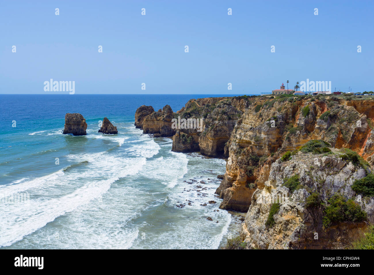 Vista lungo la costa da Ponta da Piedade con la Ponta da Piedade faro a destra, vicino a Lagos, Algarve, PORTOGALLO Foto Stock