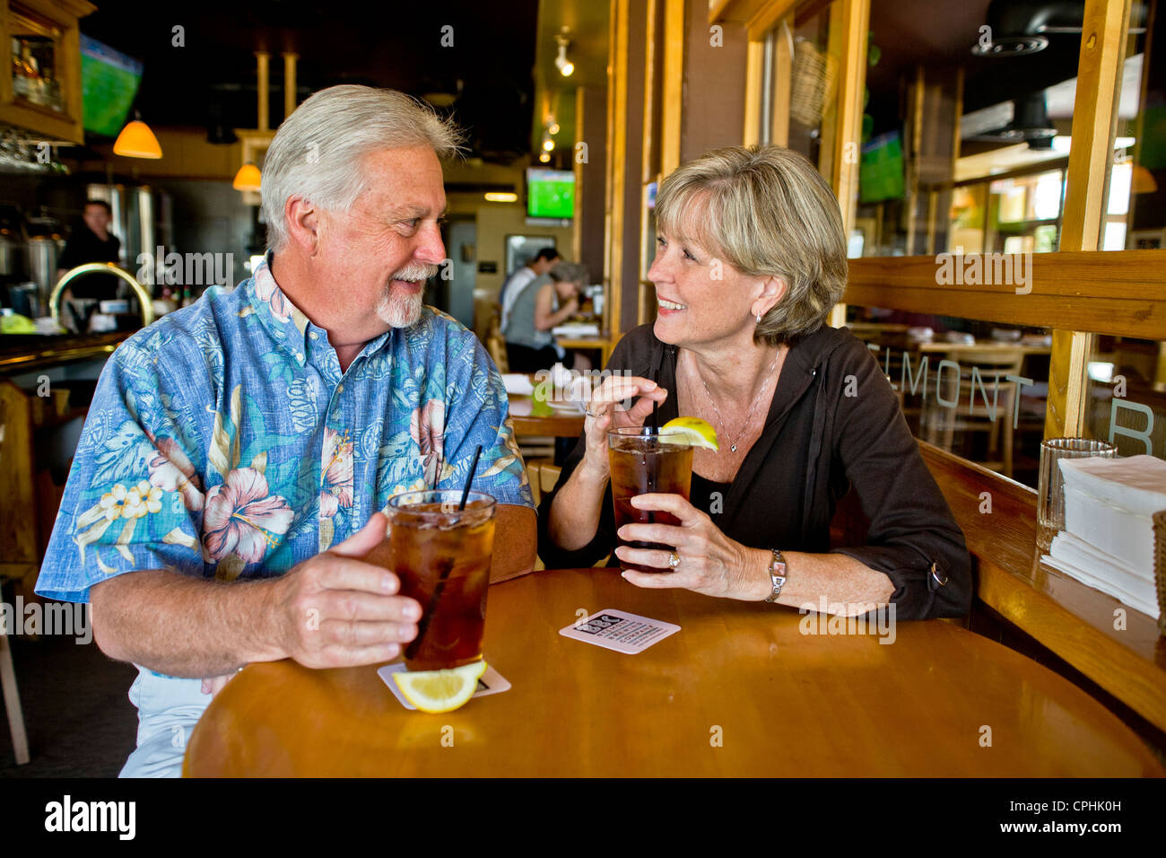Un felice medio di età compresa tra i coniugi gustare tè freddo insieme in una lunga spiaggia, CA, ristorante. Foto Stock