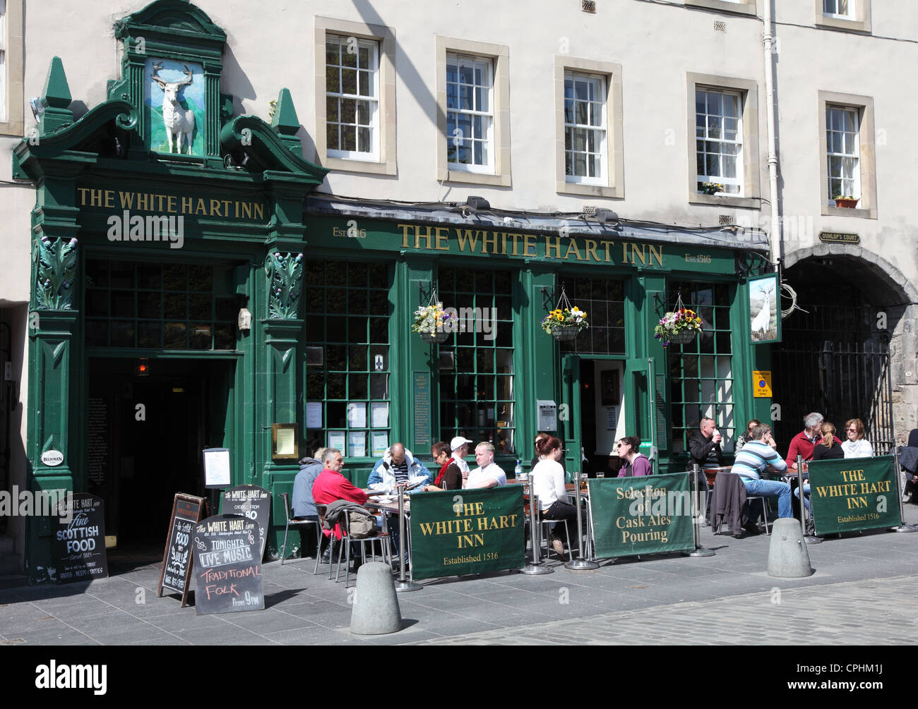 Le persone sedute a bere al di fuori del White Hart Inn entro il Grassmarket, Edimburgo Scozia UK Foto Stock