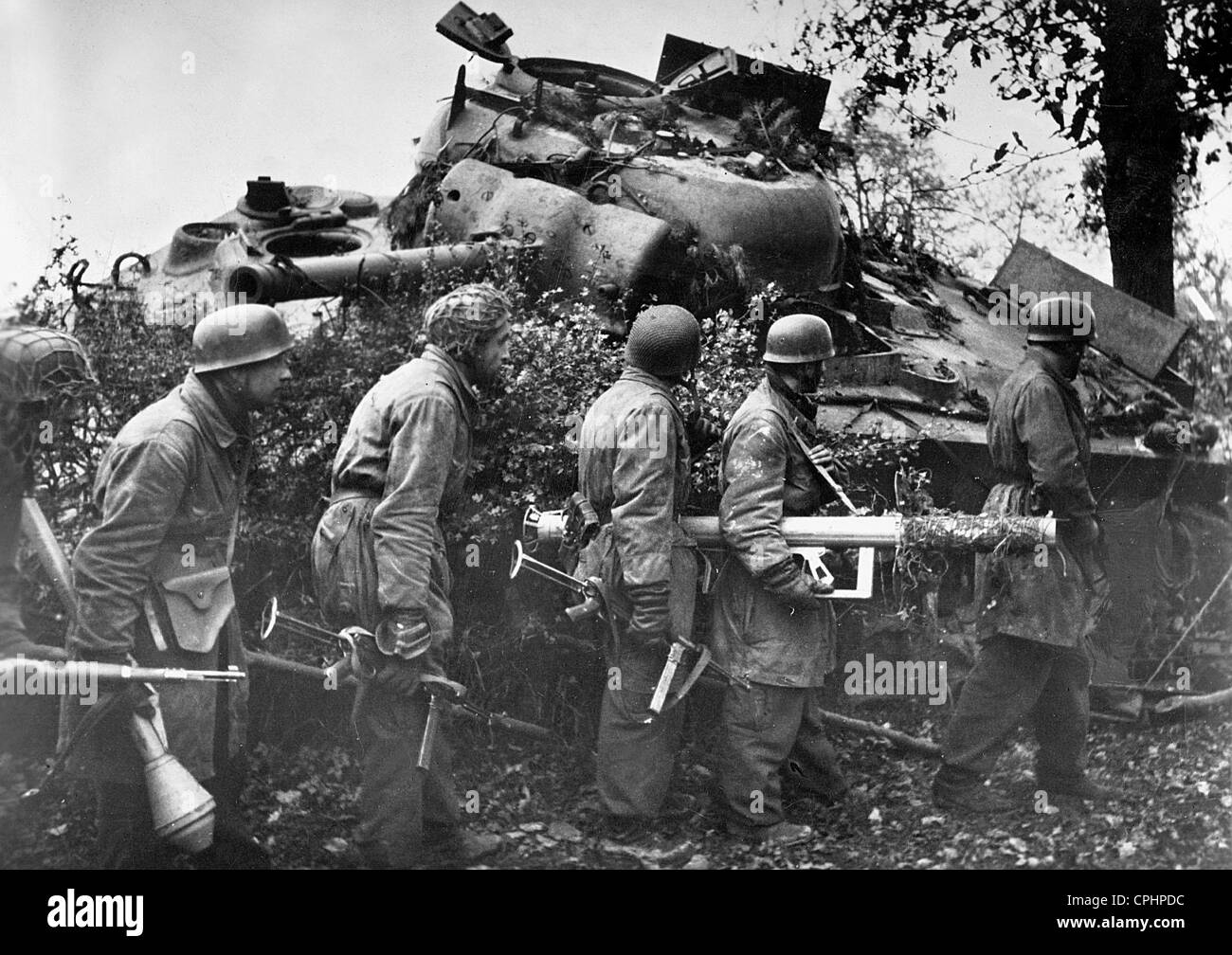 I soldati tedeschi raccolti dietro il relitto di un americano M4 Sherman serbatoio, portando anti-serbatoio armi, Olanda, 1944 (b/w Foto Stock